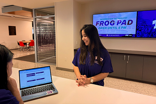 Student worker helping customer with computer at front desk